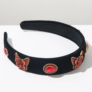 Close-up of black velvet headband with red crystals and golden butterfly ornaments