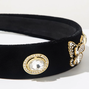 Close-up of black velvet headband featuring sparkling rhinestones and a gold butterfly