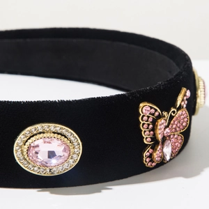 Macro detail of black velvet headband with pink gemstone and rhinestone butterfly accessory