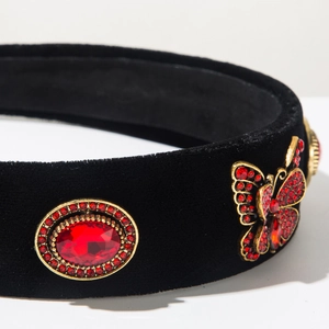 Detailed macro of velvet headband with golden butterfly metalwork and red rhinestones