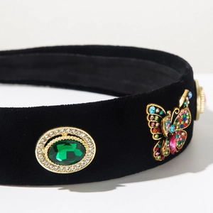 Detail of wide black velvet headband with green gemstone and colorful rhinestone butterfly