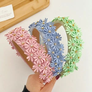 Detail of floral headbands with fabric daisies and sparkling rhinestones on wide bands