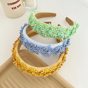 Detailed macro view of three padded headbands with colorful daisy fabric flowers and rhinestones
