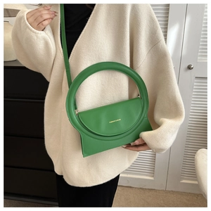 Detailansicht der grünen Ledertasche mit rundem Griff und goldenem Logo-Schriftzug