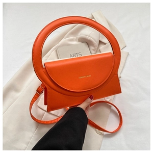 Detailansicht der stylischen orangefarbenen Handtasche mit großem Rundgriff und Gurt