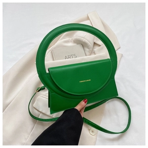 Detail der grünen minimalistischen Handtasche mit Rundgriff und goldenem Schriftzug
