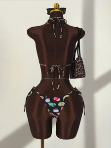 Detail of three-piece bikini set with realistic coconut and fruit print on black fabric