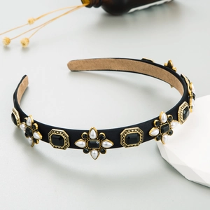 Detailed view of retro black fabric headband with gold floral pearls and rhinestones