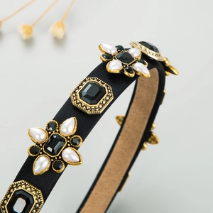 Detailed close-up of retro black fabric headband with rhinestones and pearl flower