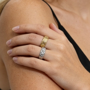 Detailed view of sun and moon embossed rings in gold and silver on a model's hand