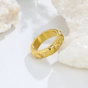 Macro view of sun and moon embossed titanium ring with matte gold finish