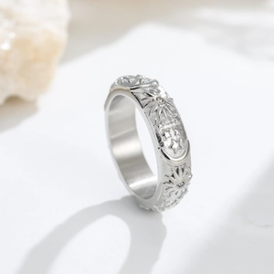 Macro detail of sun and moon relief engraving on the silver-toned wide band ring