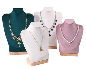Detail view of colorful velvet bust displays with wooden base showing premium necklaces