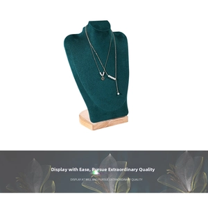 Detail of layered gold pearl necklace on green velvet bust display with wooden base