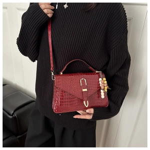 Detail of burgundy crocodile-embossed mini square bag with golden U-shaped buckle