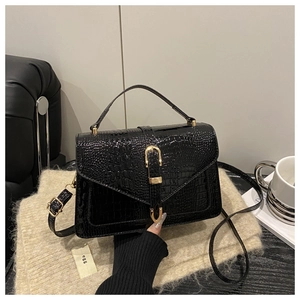 Detailed view of black crocodile pattern leather bag with gold U-shaped buckle