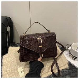Detailed view of dark coffee crocodile embossed leather texture with gold U-shaped hardware