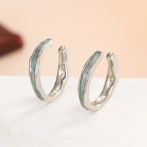 Macro shot of silver ear cuffs with irregular texture and light green enamel inlay