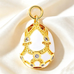 Macro detail of Faberge-style white enamel egg pendant with gold trim and crystals