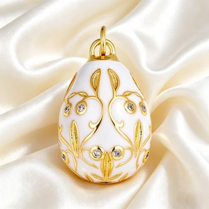 Macro view of Faberge-style white enamel egg pendant with gold vine pattern and cubic zirconia