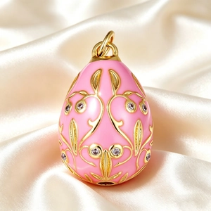 Macro detail of pink enamel egg pendant with gold floral patterns and clear crystals