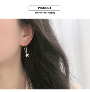 Détail de boucles d'oreilles pendantes étoile en plaqué or 18K sur un modèle