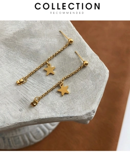 Gros plan de boucles d'oreilles étoile dorée avec chaîne pendante sur support en pierre