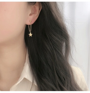 Détail de boucles d'oreilles à pompons étoiles plaquées or 18 carats sur un modèle