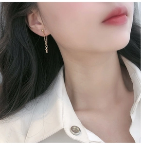 Gros plan de boucles d'oreilles pendantes étoile en or 18K sur l'oreille d'un mannequin
