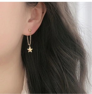 Détail de la boucle d'oreille étoile plaquée or 18K avec chaîne pendante sur le modèle