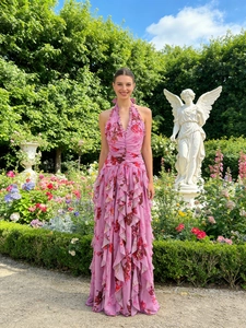 Pink floral halter maxi dress with ruffle details standing in a romantic garden setting