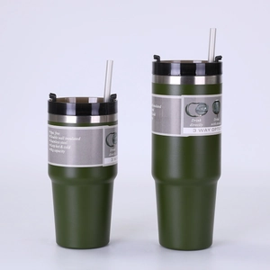 Detail of dark green double-wall vacuum insulated stainless steel cup with straw