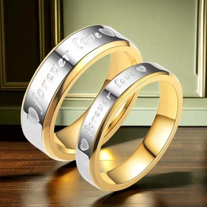 Detail of couple rings set engraved with Forever Love on two-tone stainless steel bands