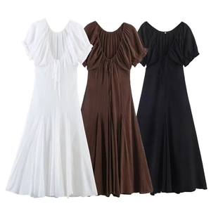 Detailed view of pleated midi dresses in white, brown, and black with strappy V-neckline