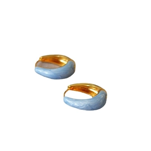 Orecchini a cerchio in ottone dorato con smalto marmorizzato blu su sfondo bianco neutro