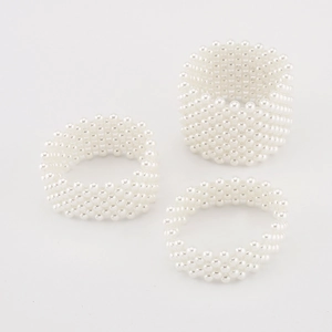 Detail of multi-row elastic pearl beaded bracelets in pure white on a minimalist background