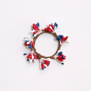 Close-up of pine needle napkin ring with festive red, white, and blue berry clusters