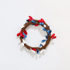 Detail of red white and blue pip berry candle ring with natural brown grapevine base