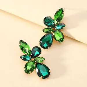 Retro oversized gold earrings with green glass crystals in leaf pendant design