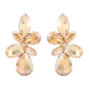 Macro detail of champagne glass leaf earrings with faceted stones and golden claw setting