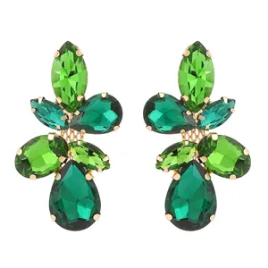Macro shot of green crystal leaf earrings with gold metal prongs and multi-faceted stones