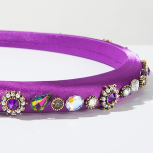Detailed close-up of purple satin headband with rhinestones and floral crystal clusters