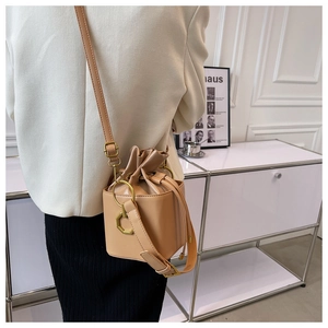 Detail of warm apricot leather bucket bag with gold hardware and drawstring closure