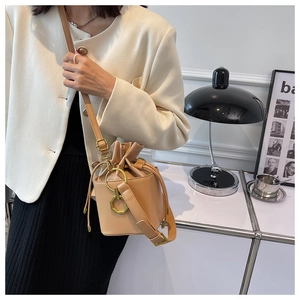 Detail of vintage beige drawstring bucket bag with gold hardware ring and adjustable strap