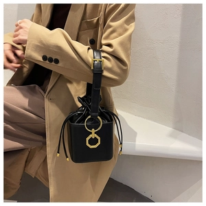 Close-up of black leather bucket bag with gold geometric buckle and drawstring detail