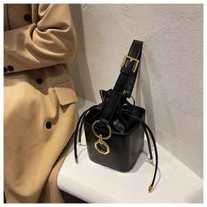 Detail of black matte leather bucket bag with gold rings and drawstring inner pocket