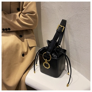 Detail of black matte leather bucket bag with gold ring hardware and drawstring closure