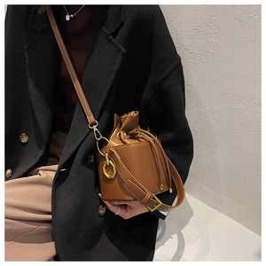 Detail of a brown bucket bag with gold hexagonal hardware and drawstring closure