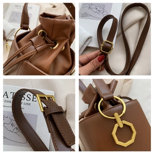 Detail view of brown leather bucket bag with gold hardware and drawstring closure
