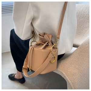Detail of a khaki bucket bag featuring a drawstring closure and gold octagonal hardware